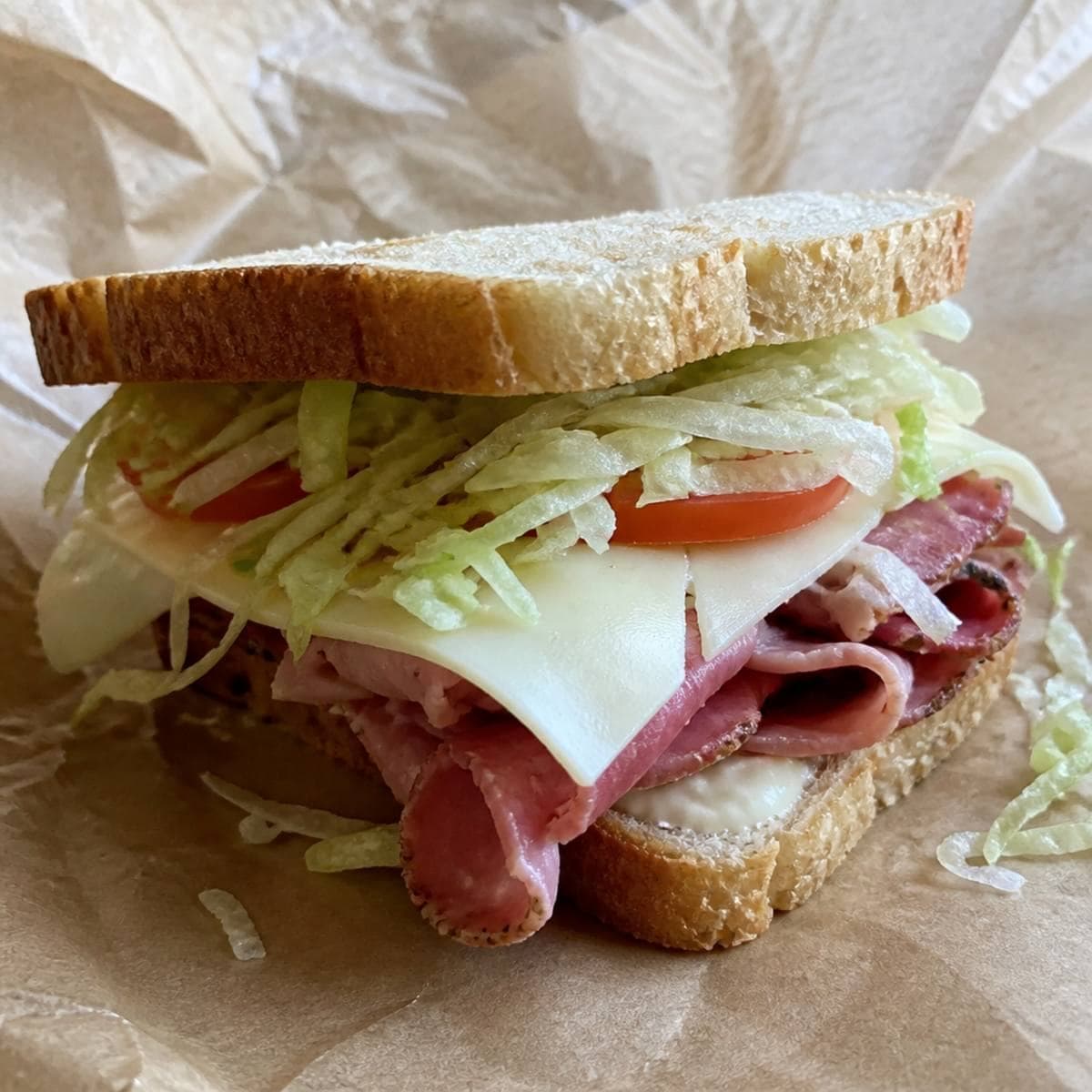 Deli owner handing a wrapped sub across the counter